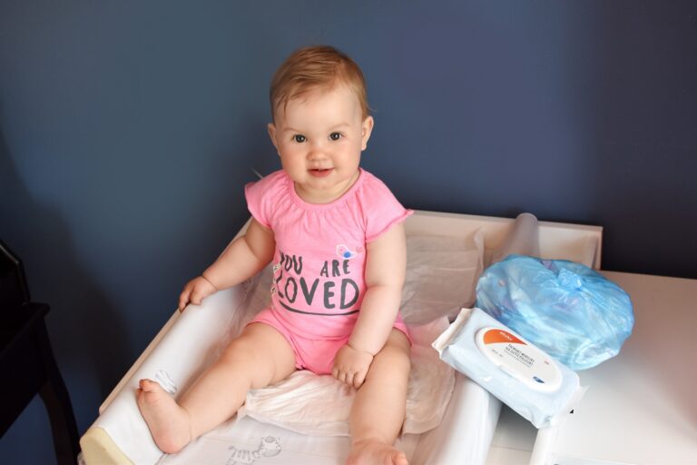 Niemowlę na przewijaku plus woreczki na zużyte pieluszki.